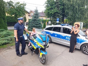 Policjant asystuje dziecku na motocyklu.