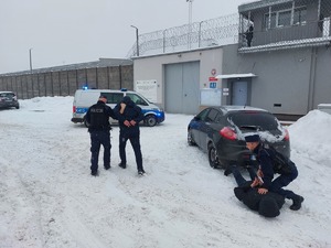 Policjanci transportują zatrzymanych do radiowozu