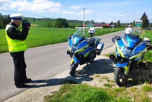 Stojące dwa motocykle służbowe, policjant z miernikiem prędkości.