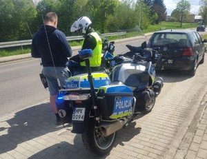 Motocykl służbowy stojący przy drodze wraz z Policjantem Wydziału Ruchu Drogowego KPP Dębica wraz z kierującym i jego pojazdem.