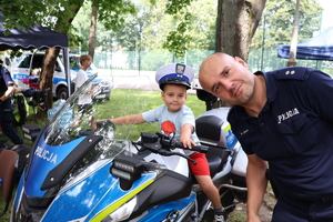 Policjant podczas pikniku rodzinnego z chłopcem na motocyklu